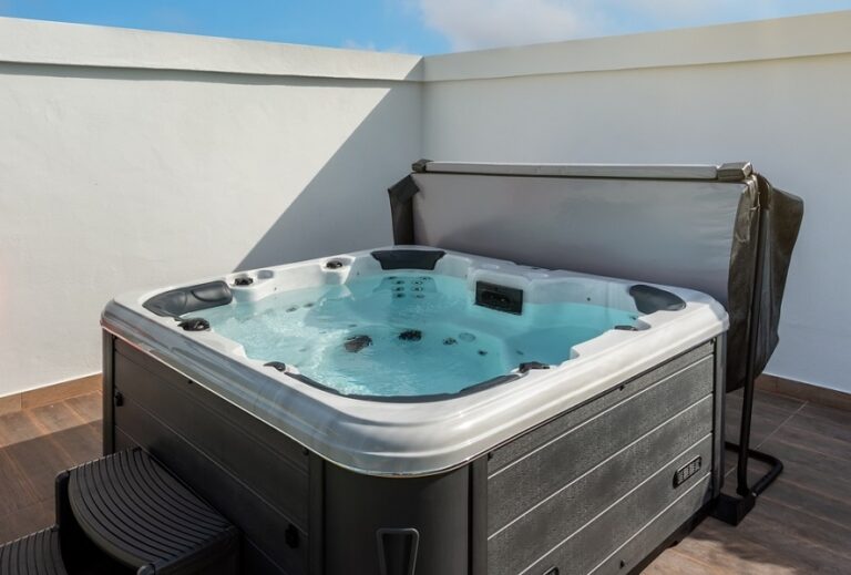 Hot Tub with blue clear water and Cover Lifter in an outdoor home garden