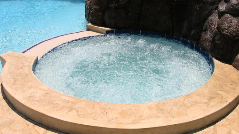 A concrete made inground hot tub filled with water and working jets.