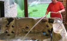 a man filing a hot tub with a garden house pipe after cleaning it