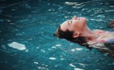 A woman enjoying reverse swimming in a blue water hot tub. (The Negative Effects of Hot Tubs)