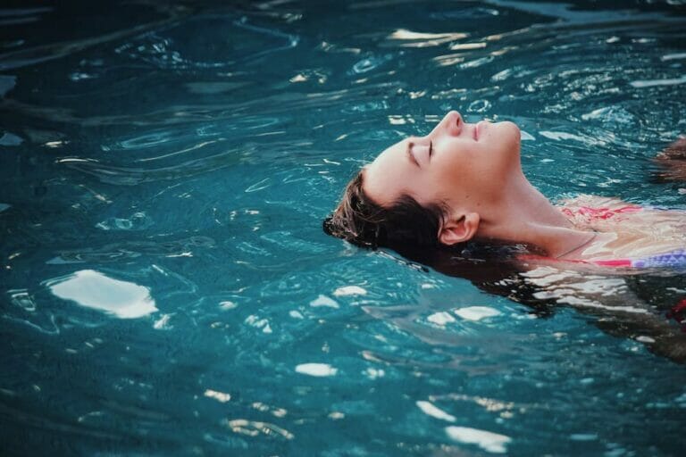 A woman enjoying reverse swimming in a blue water hot tub. (The Negative Effects of Hot Tubs)