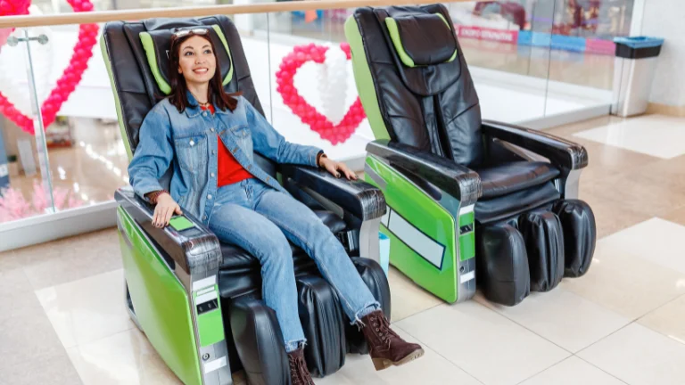 A woman wearing a red shirt and jeans pant checks a massage chair to buying.