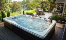 A young couple relaxing and enjoying a swim spa in a home garden.