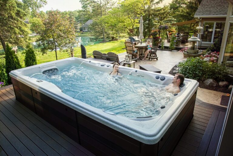 A young couple relaxing and enjoying a swim spa in a home garden.