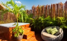 A tropical themed outdoor patio with a hot tub and seating area.