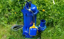 A brand new submersible pump placed on the grass in a garden, ready for use.