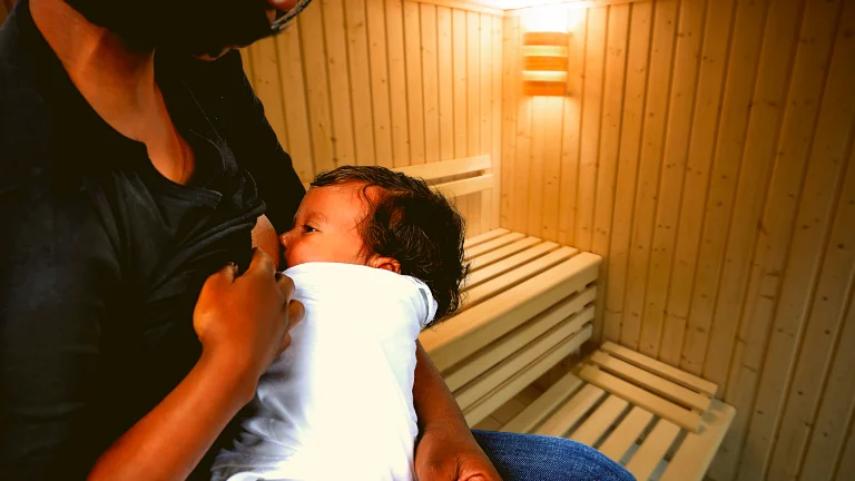 The mother nourishes her child with care in a sauna setting. (Can I Do Sauna while Breastfeeding)