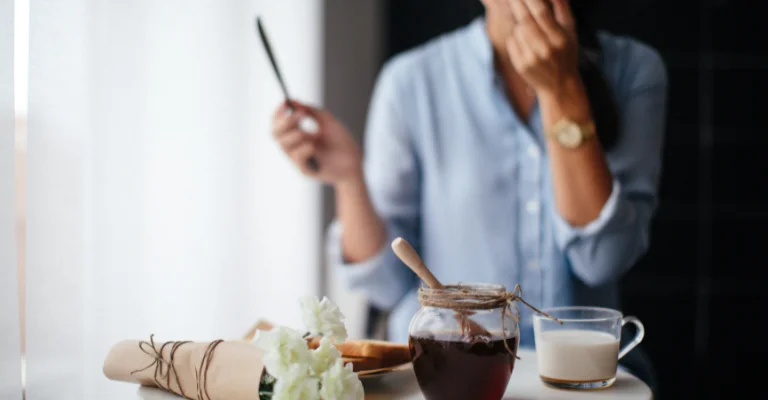 A woman eating honey and a knife at the breakfast table. (Do all countries that have bees also eat honey)