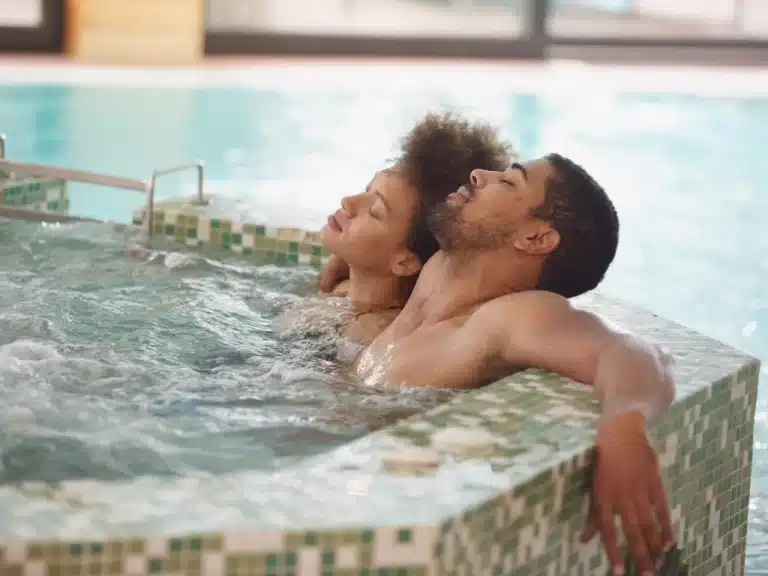 Two young couples enjoying a blissful soak in a hot tub, closing their eyes in pure relaxation.