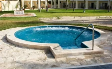 A traditional hot tub with clear blue water and concrete handrail