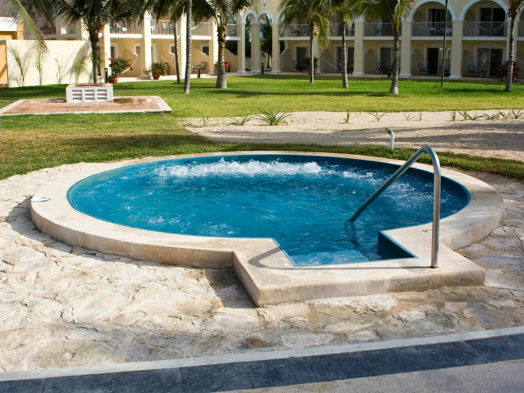 A traditional hot tub with clear blue water and concrete handrail