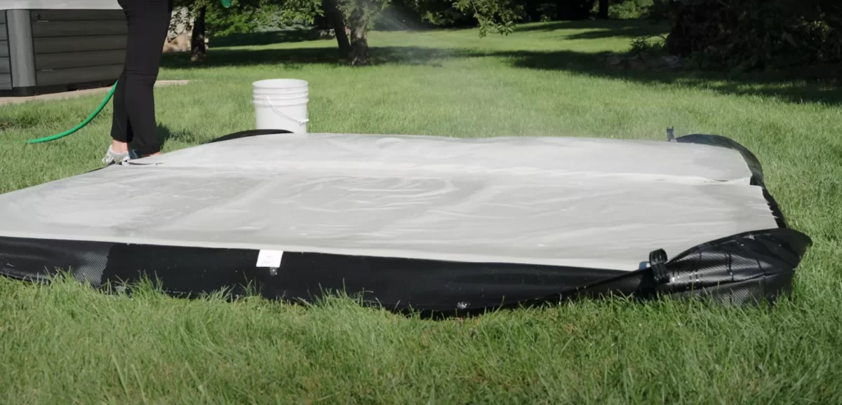 A person cleaning a vinyl hot tub cover with hose pipe. 