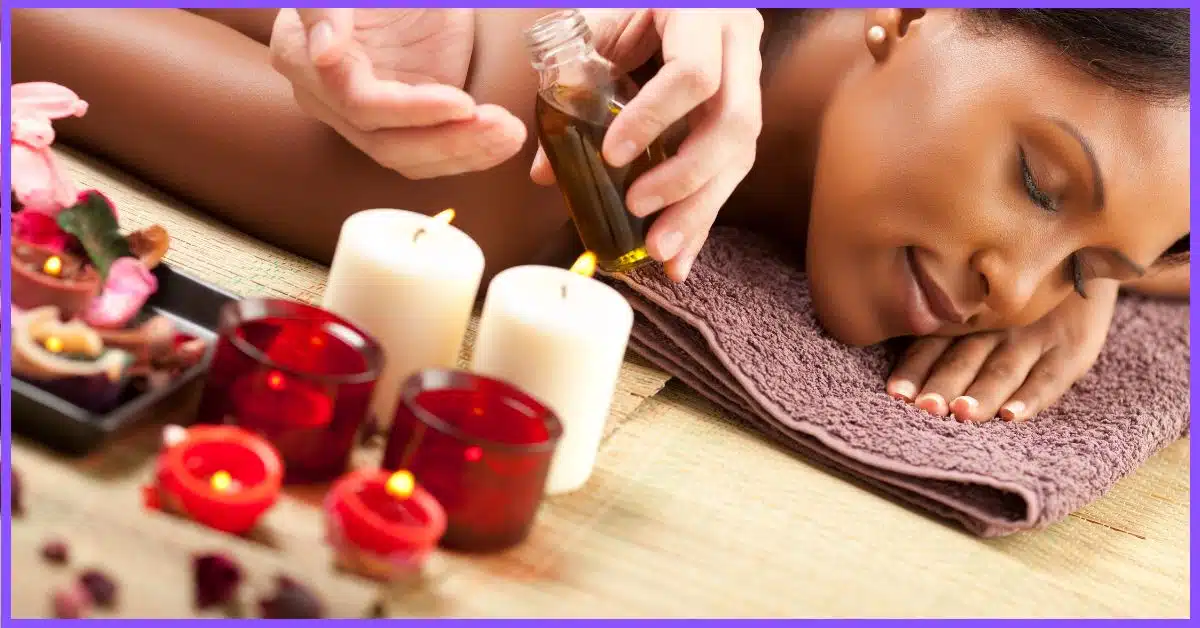 A woman receiving a Booty Hip Lifting Massage on a table, surrounded by candles and covered in oil.