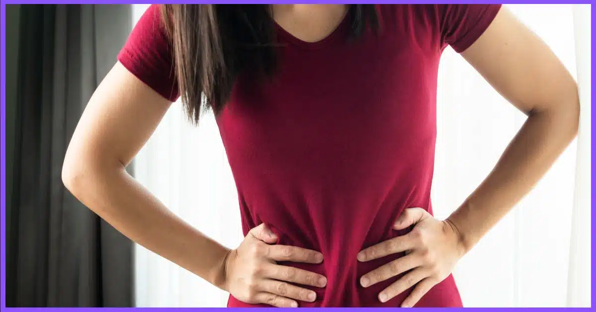 A woman in a red shirt clutching her stomach in discomfort. (Getting a Massage on Your Period)