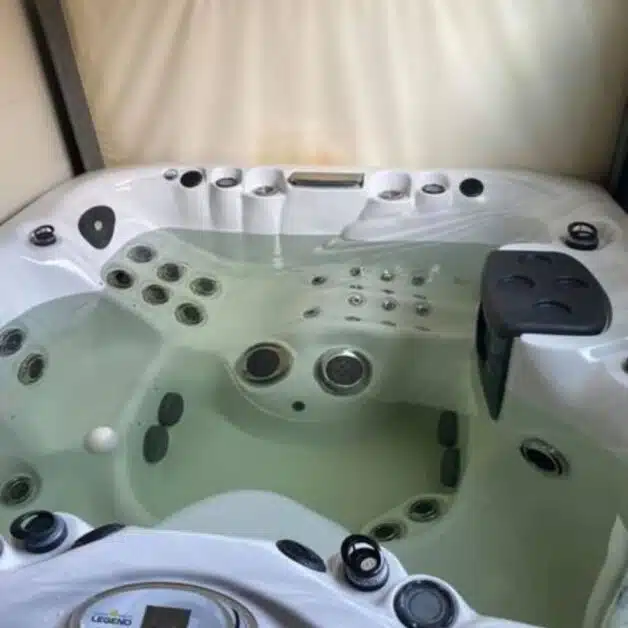 a hot tub with a white interior and black exterior, filled with brown water. (Brown Water in Your Hot Tub)