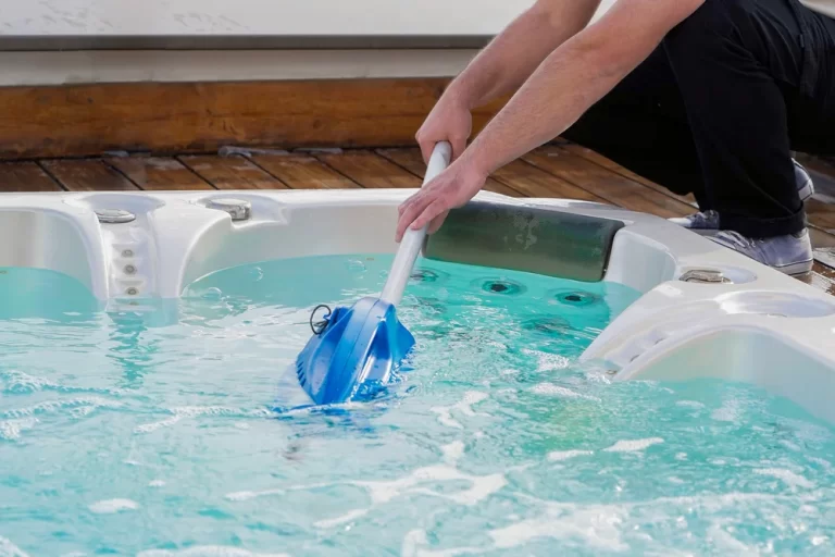 A man cleaning and refilling a blue water hot tub.