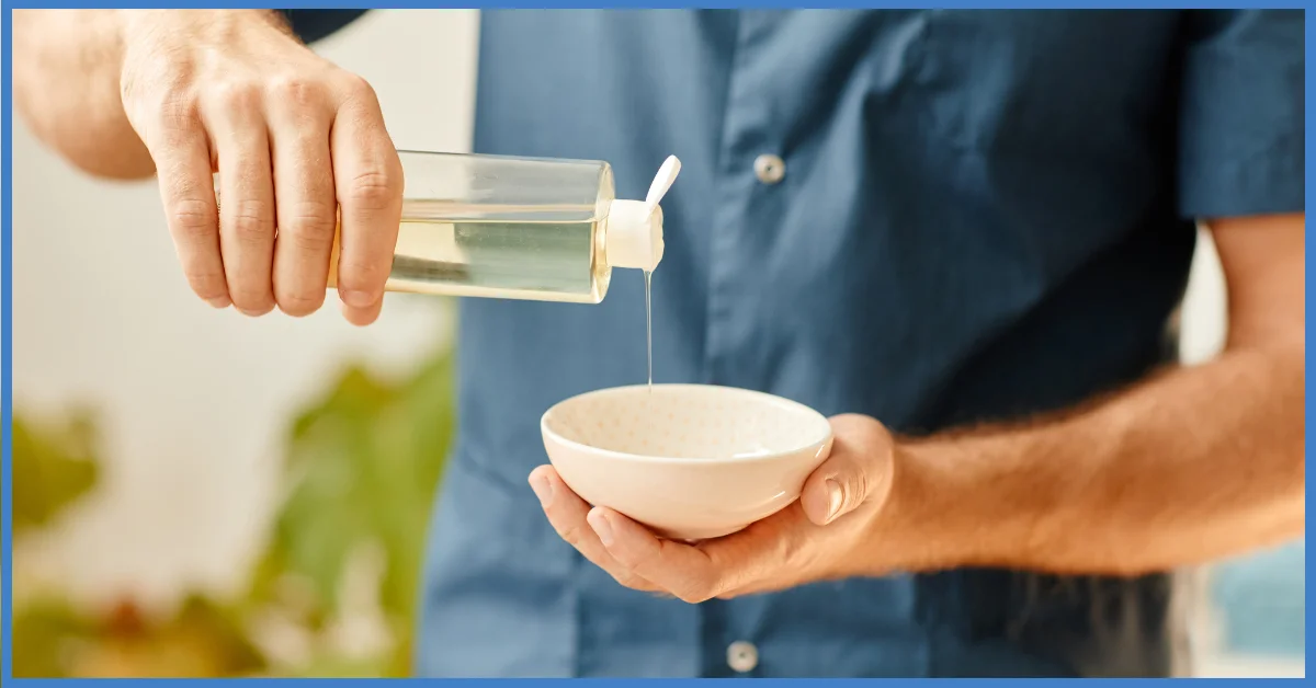 A man wearing a blue shirt poured liquid from a bottle into a bowl. (Massage Oils Bath and Body Works)