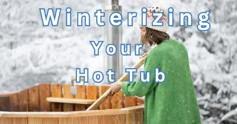 A person in a green robe and a winter hat cleaning a wooden hot tub in a snowy forest.