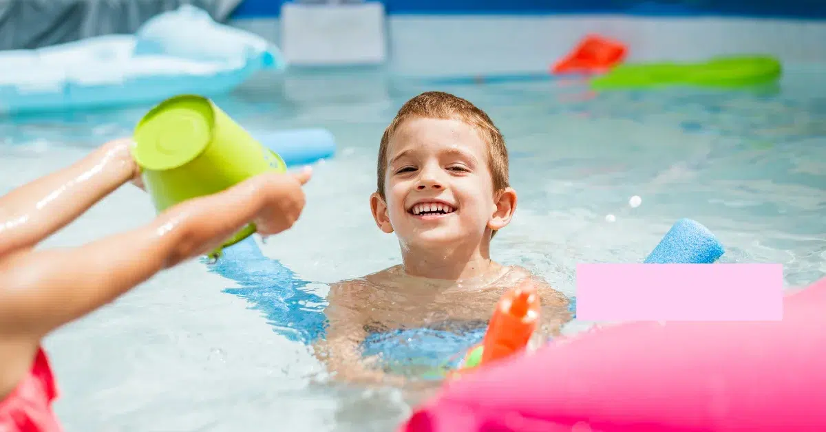  A group of four children having fun with various pool toys in a blue swimming pool.