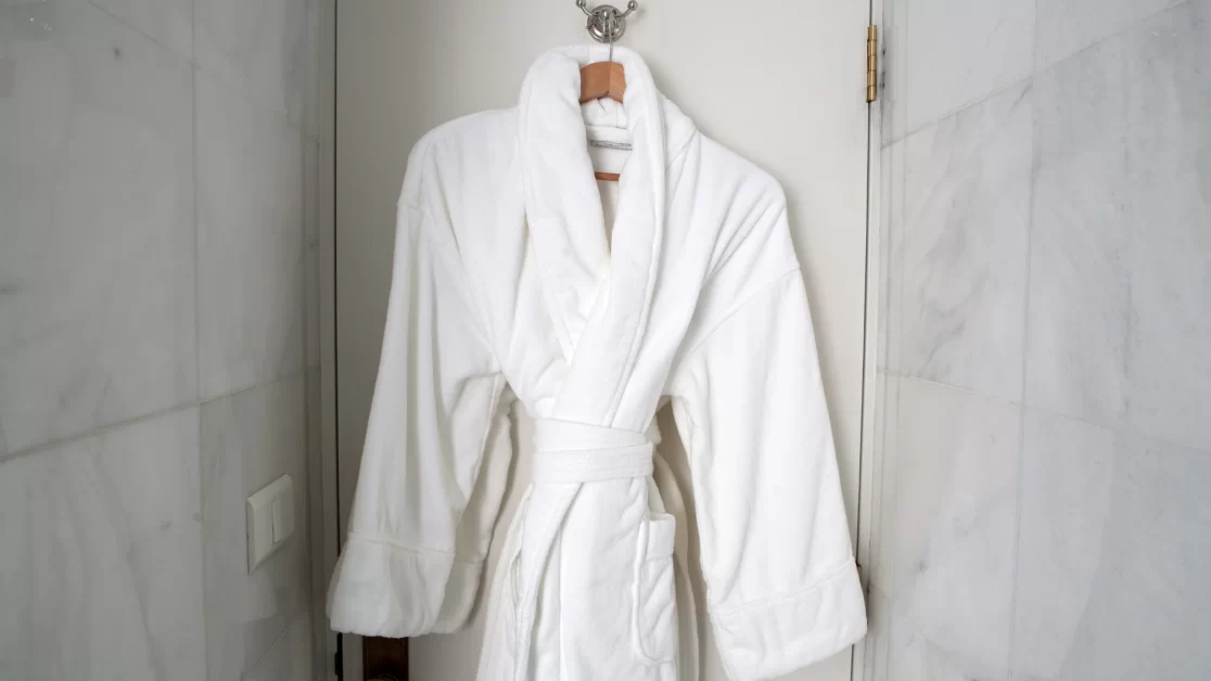 A terry cloth robe hang on a wall.