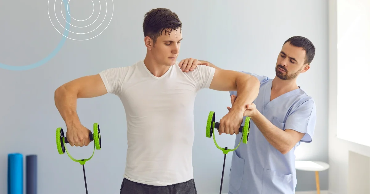 Two individuals engaged in a physical therapy session. One person, wearing a white t-shirt and black pants, is performing an exercise with green resistance bands, stretching the arms behind the back.