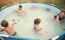 Children happily splashing, jumping, and playing in an inflatable hot tub.