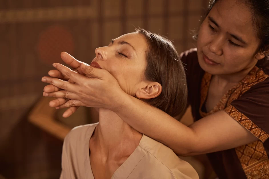 A practitioner performing traditional Eastern massage using foot pressure on a client’s back.