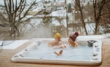 Elderly couple relaxing in a hot tub, surrounded by nature, with the water temperature set to a comfortable 104°F.