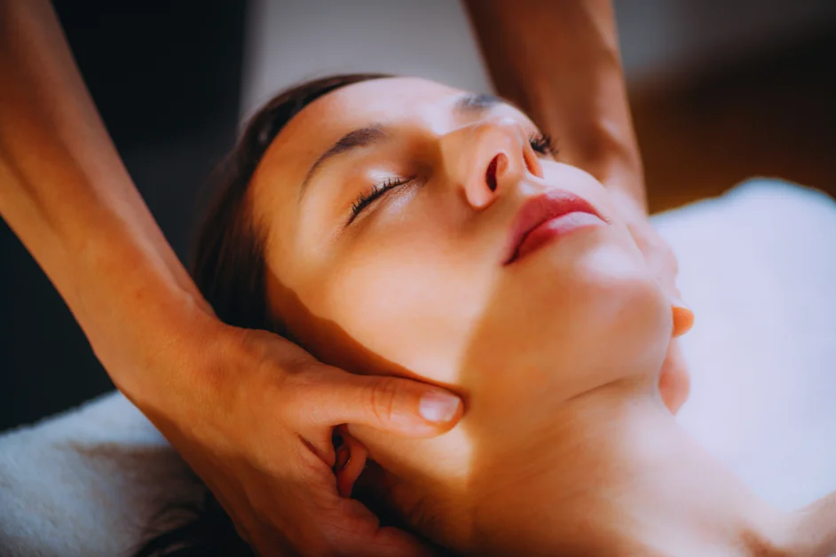 Close-up view of a massage therapist’s hands applying pressure to a client’s shoulder or upper back during a therapy session, with part of the image intentionally blurred.