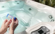 A man checking hot tub water with testing stick.