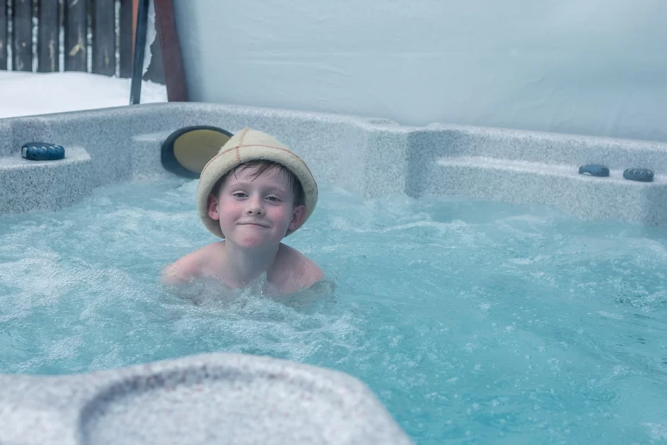 A cheerful family with children enjoying a relaxing hot bath together, smiling and splashing water.