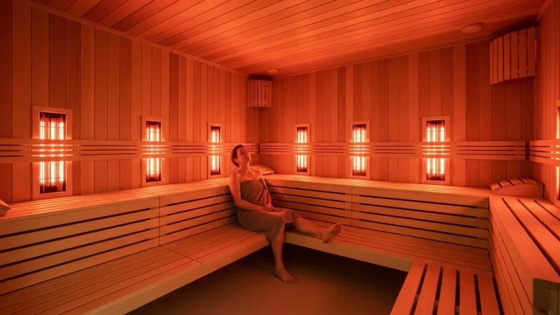 Optimal Sauna Temperature: Why Hotter Isn’t Always Better 3 Modern infrared sauna with glowing heating panels and a relaxed person enjoying gentle heat.